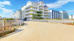 A beachfront hotel with multiple balconies, a sandy beach in front, and a clear blue sky.