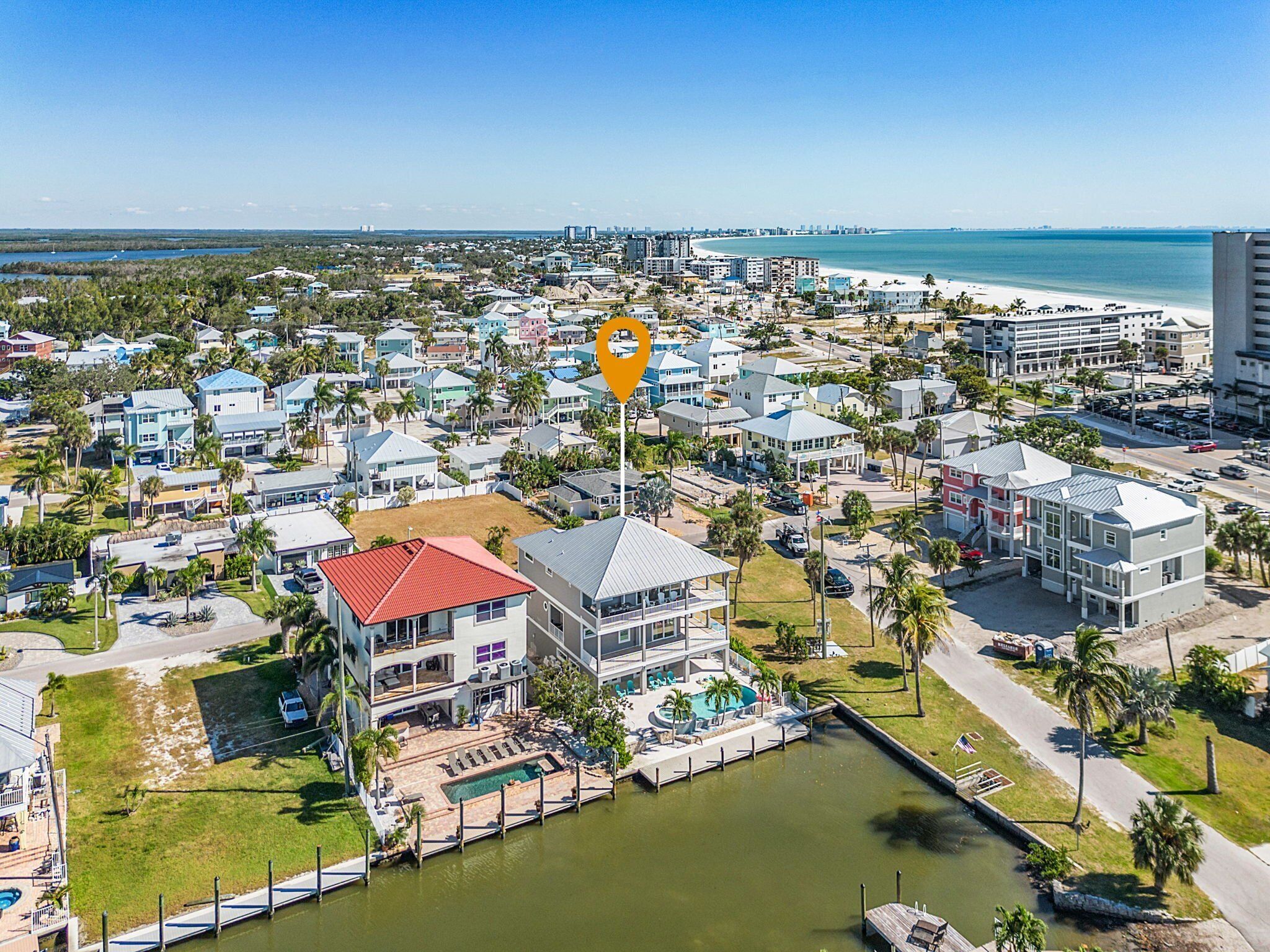 An aerial view of a coastal residential area with a marina, houses, and a large building with a red roof.