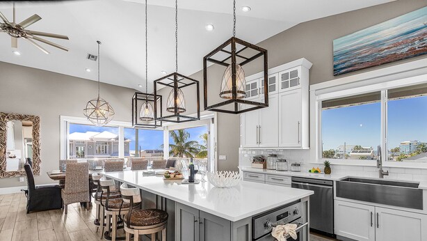 Una cocina moderna con una isla grande, armarios blancos y vistas al exterior.
