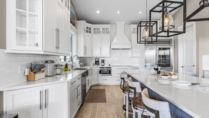 Una cocina moderna con armarios blancos, una isla central e iluminación colgante.