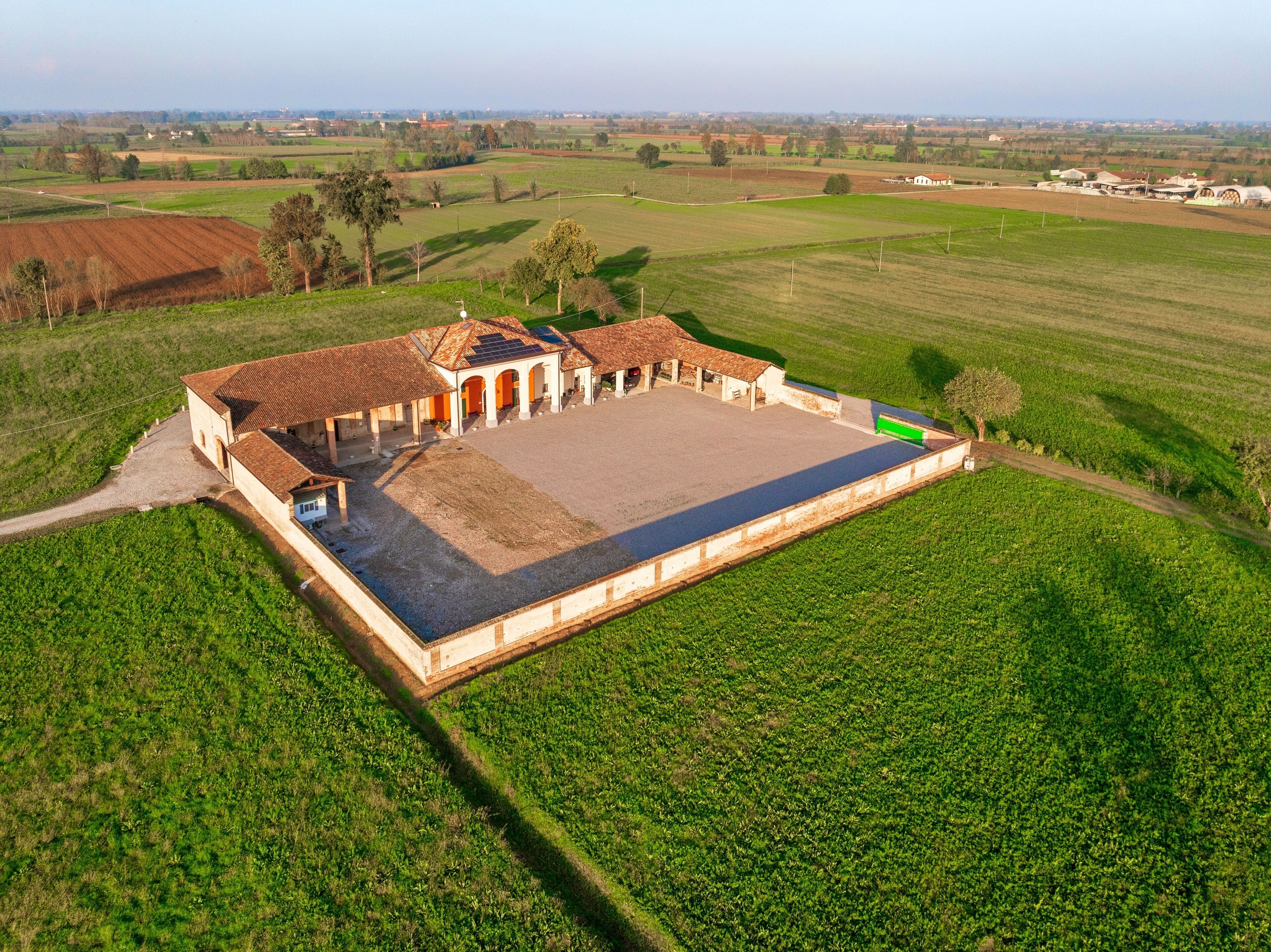 A large, open building with a central courtyard surrounded by fields.