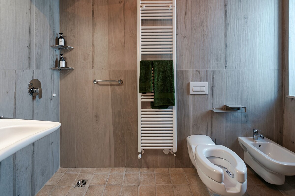 A modern bathroom with a toilet, bidet, and a built-in towel rack.