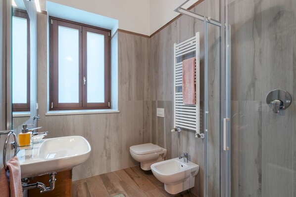 A modern bathroom with a large sink, toilet, bidet, and a glass shower enclosure. - Agriturismo Cascina Tavolette (Pralboino)