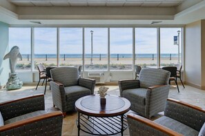 A room with large windows, a round table, and four upholstered chairs. - Oceanfront Beach Condo, Pool, Gym, Fishing Surfing (Virginia Beach)