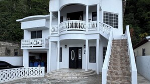 Un bâtiment à deux étages doté d’un balcon, d’un escalier et d’une porte d’entrée.