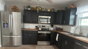 A modern kitchen with dark cabinets, stainless steel appliances, and a wooden countertop. - Welcome to Rivers Edge Retreat – Your Serene Escape on the Osage River (Jefferson City)
