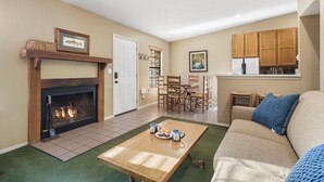 A living room with a fireplace, a dining area, and a kitchen.
