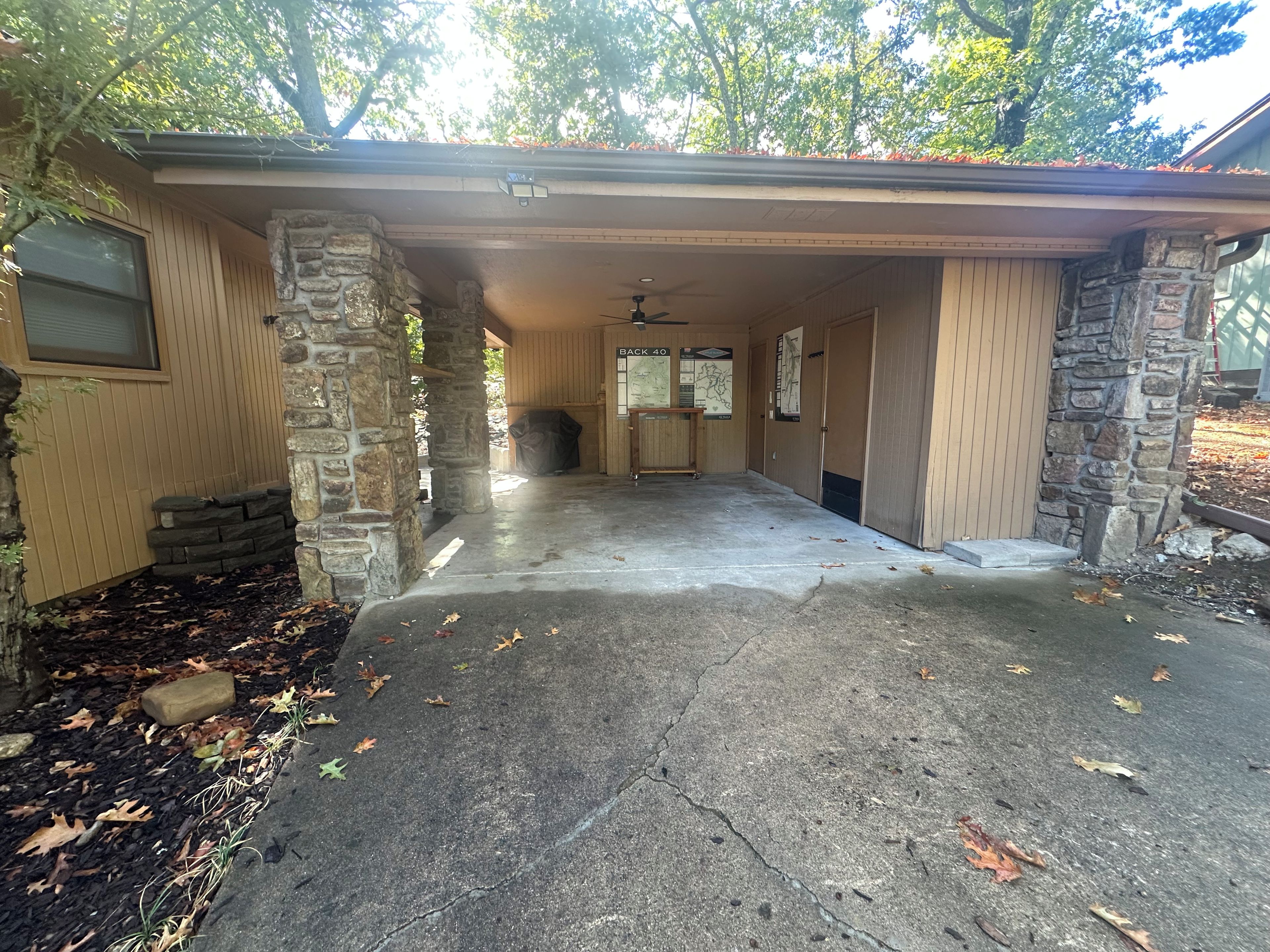 A garage with a concrete floor, stone pillars, and a covered entrance.