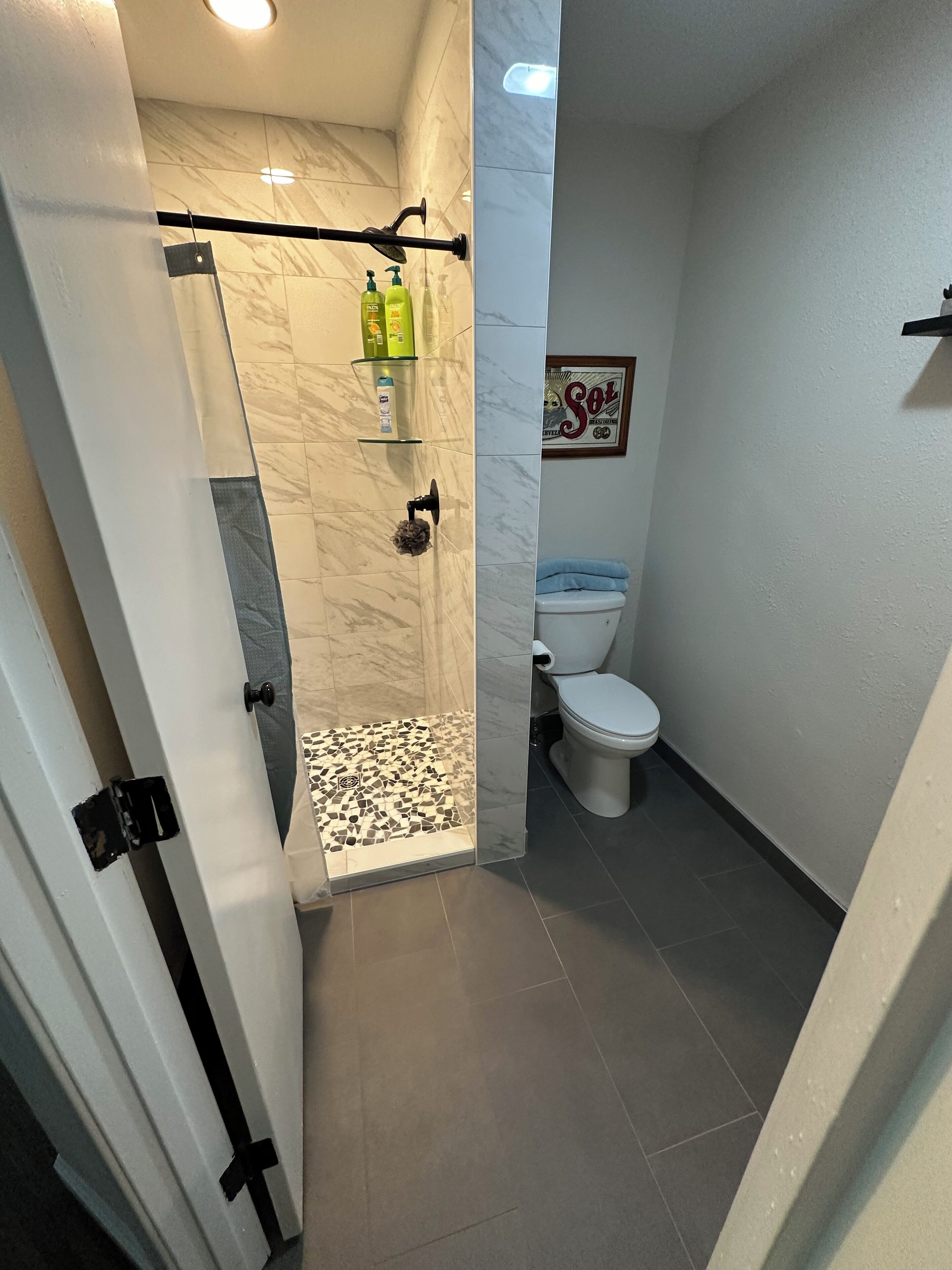 Une salle de bain avec douche, toilettes et carrelage en marbre.