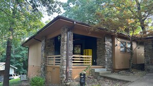 A rustic cabin with a stone exterior, a wooden porch, and a bear statue in front. - Cozy cabin in serene Bella Vista with WiFi and AC (Bella Vista)