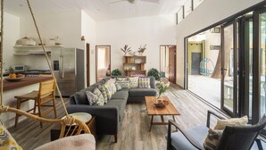 A spacious living area with a modern kitchen, a large sofa, and a dining table. - Oceano5, 4 bedroom Pool Villa - 4 min walk to the beach (nosara)