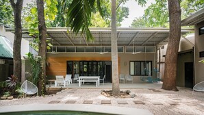 A modern outdoor pool area with a covered seating area, surrounded by trees and plants. - Oceano5, 4 bedroom Pool Villa - 4 min walk to the beach (nosara)