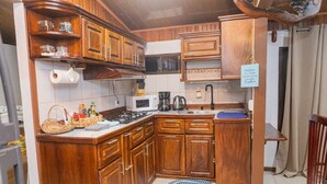 Een kleine keuken met houten kastjes, een magnetron, een fornuis en een spoelbak.