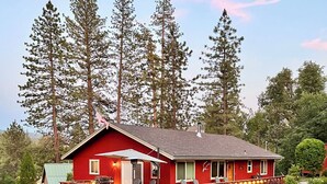 Une maison rouge avec une terrasse en bois, un jacuzzi et un toboggan.