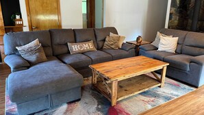 Un canapé modulable agrémenté d’un coussin orné du mot « HOME », une table basse en bois et un tapis à motifs.