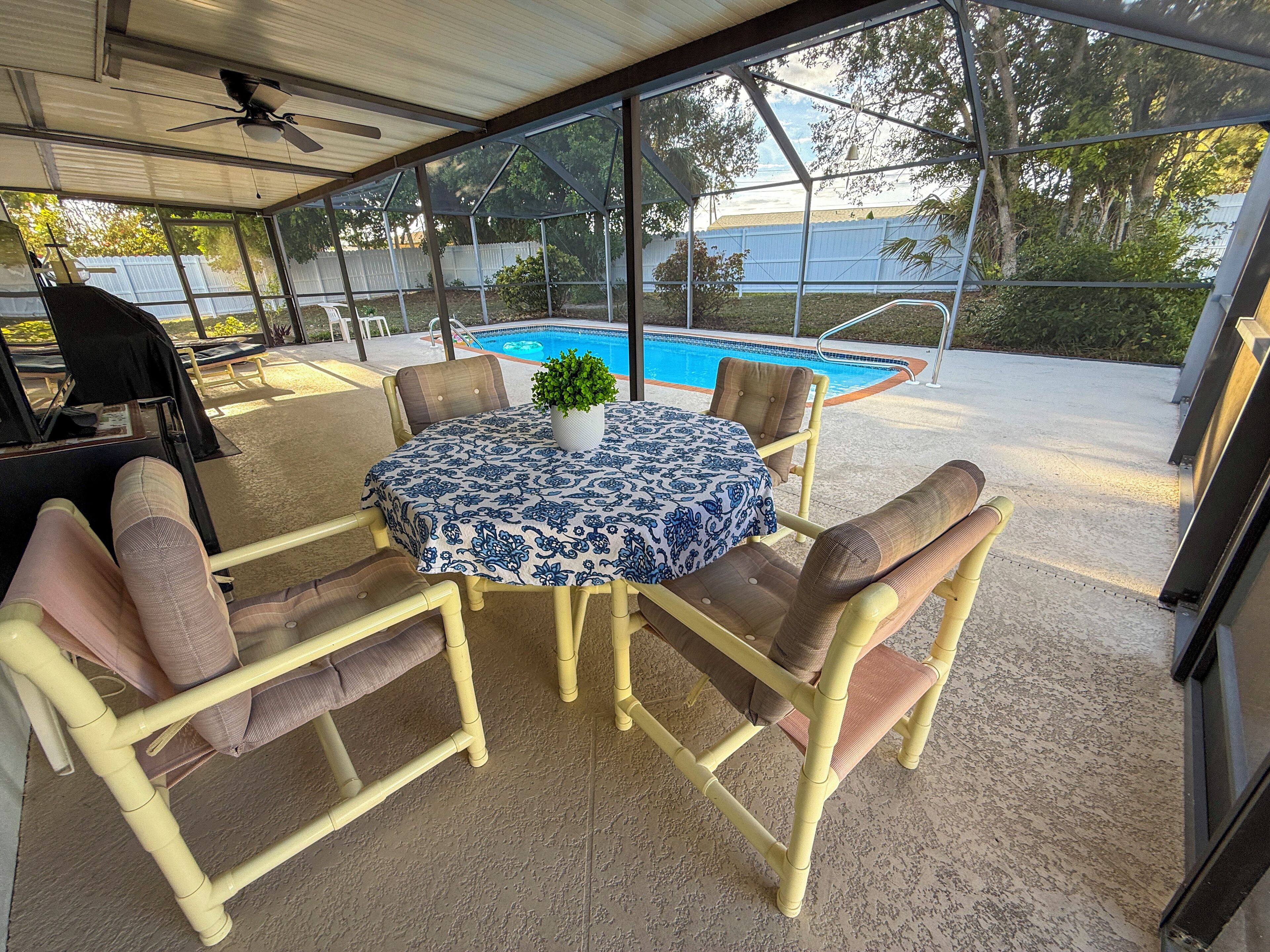 Une terrasse extérieure avec une table ronde, des chaises et une vue sur une piscine.