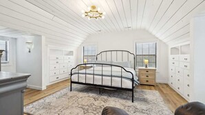 Een slaapkamer met een bed, nachtkastjes, een kaptafel en een kroonluchter.