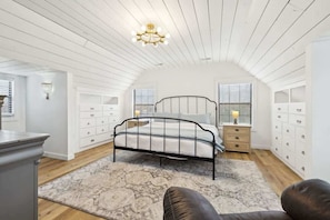 Une chambre à coucher avec un lit, des tables de chevet, une commode et un lustre.