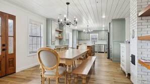 Een ruime keuken met houten kastjes, een eettafel met stoelen en een kroonluchter.