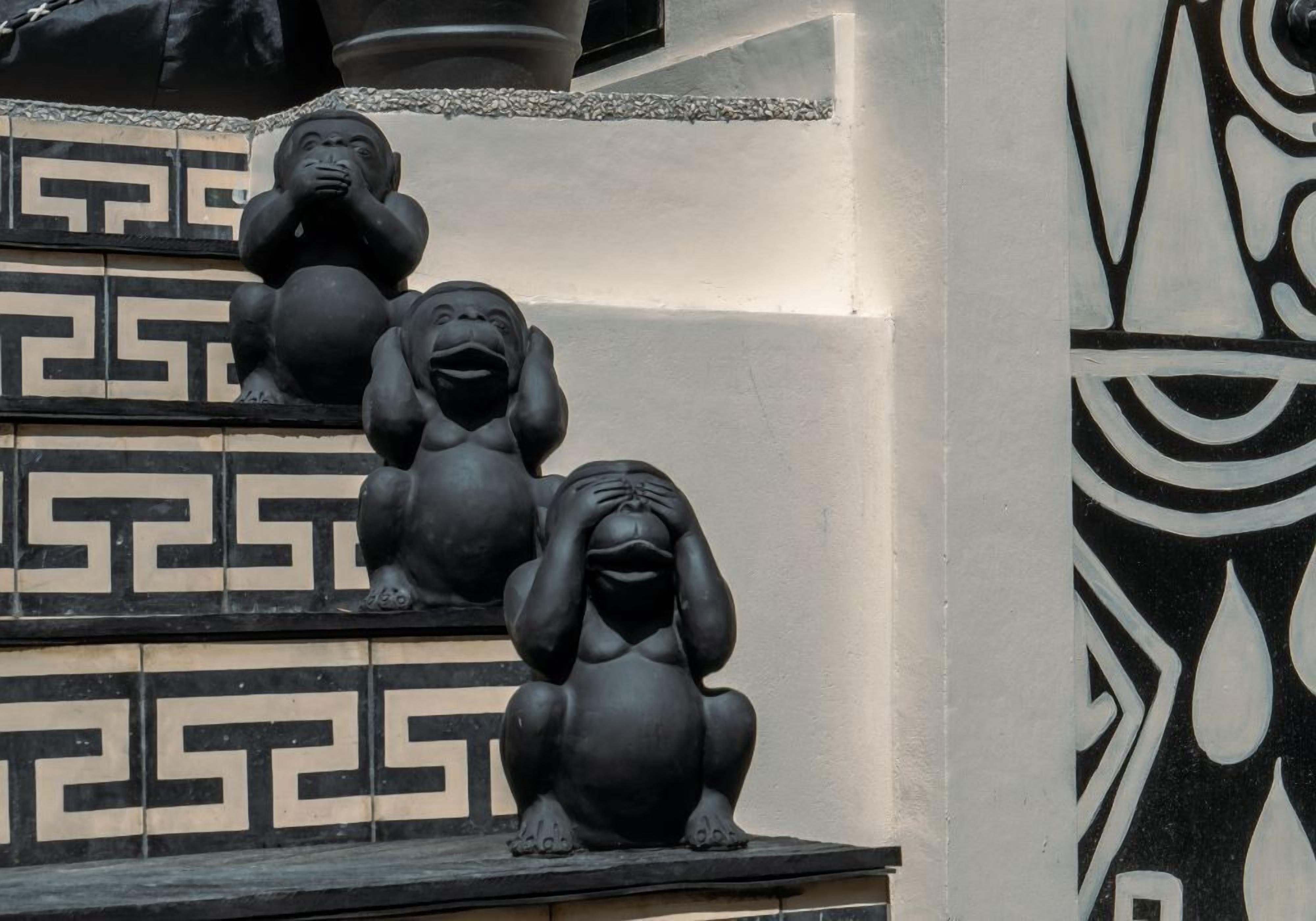 A staircase with black and white patterned steps and three black statues of gorillas.