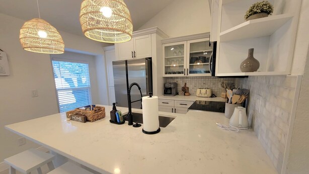 Una cocina moderna con armarios blancos, una isla grande con taburetes de bar, una cafetera y un tostador.