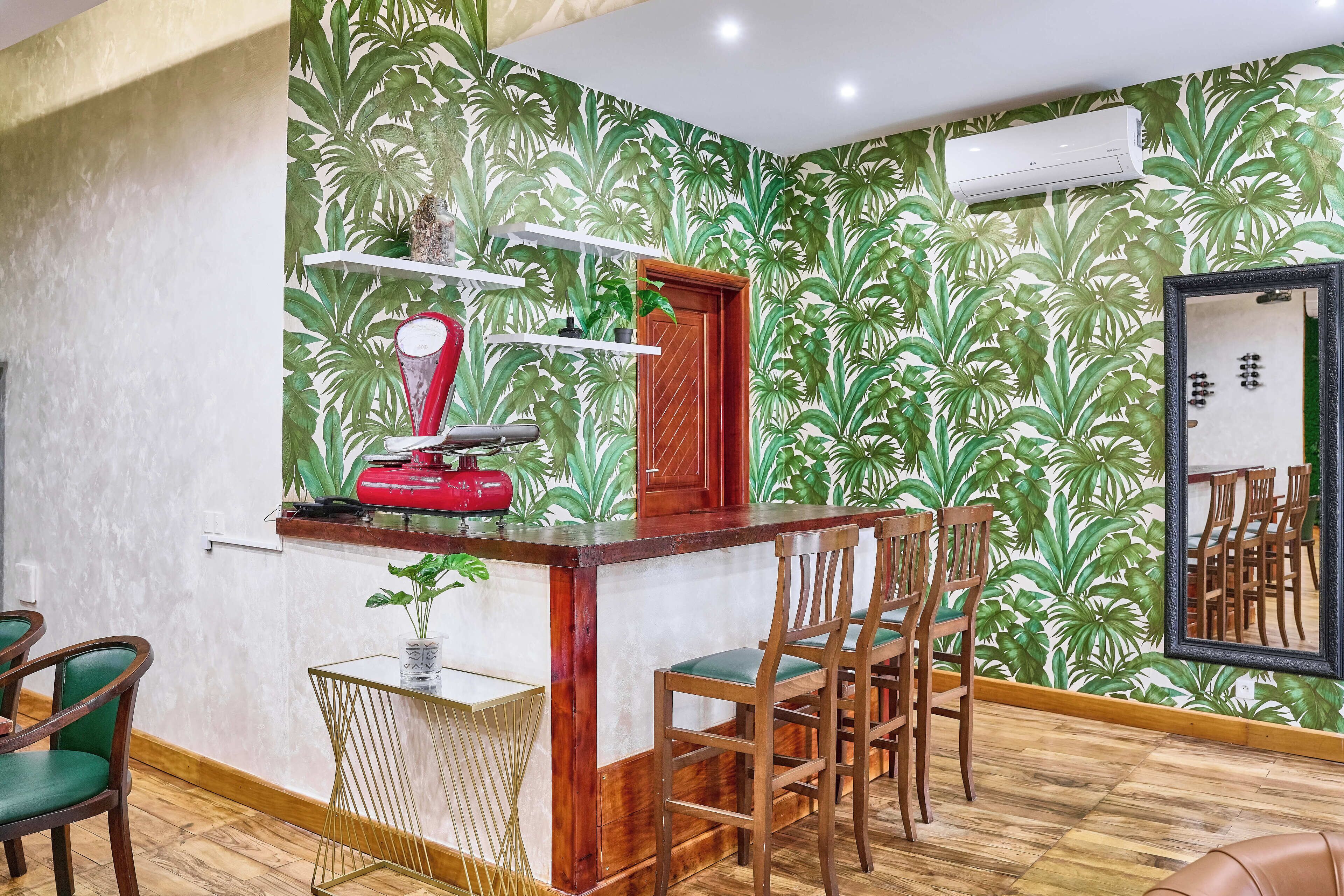 Una zona de bar con mostrador de madera, sillas verdes y un espejo.