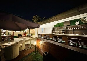 An outdoor bar area with wicker furniture, a counter, and a clock on the wall.