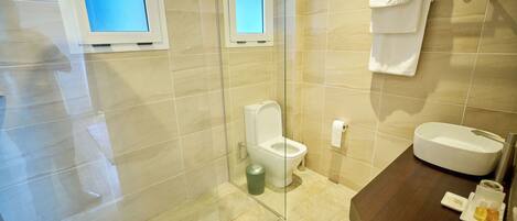A modern bathroom with a glass-enclosed shower, a toilet, a sink with a mirror, and a towel rack.