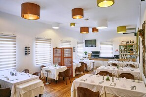 A restaurant with multiple tables set for dining, featuring a variety of table settings and a wooden floor.