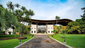 A building with a large entrance, surrounded by well-maintained lawns and palm trees. - Roma Hôtel & Restaurant (Libreville)