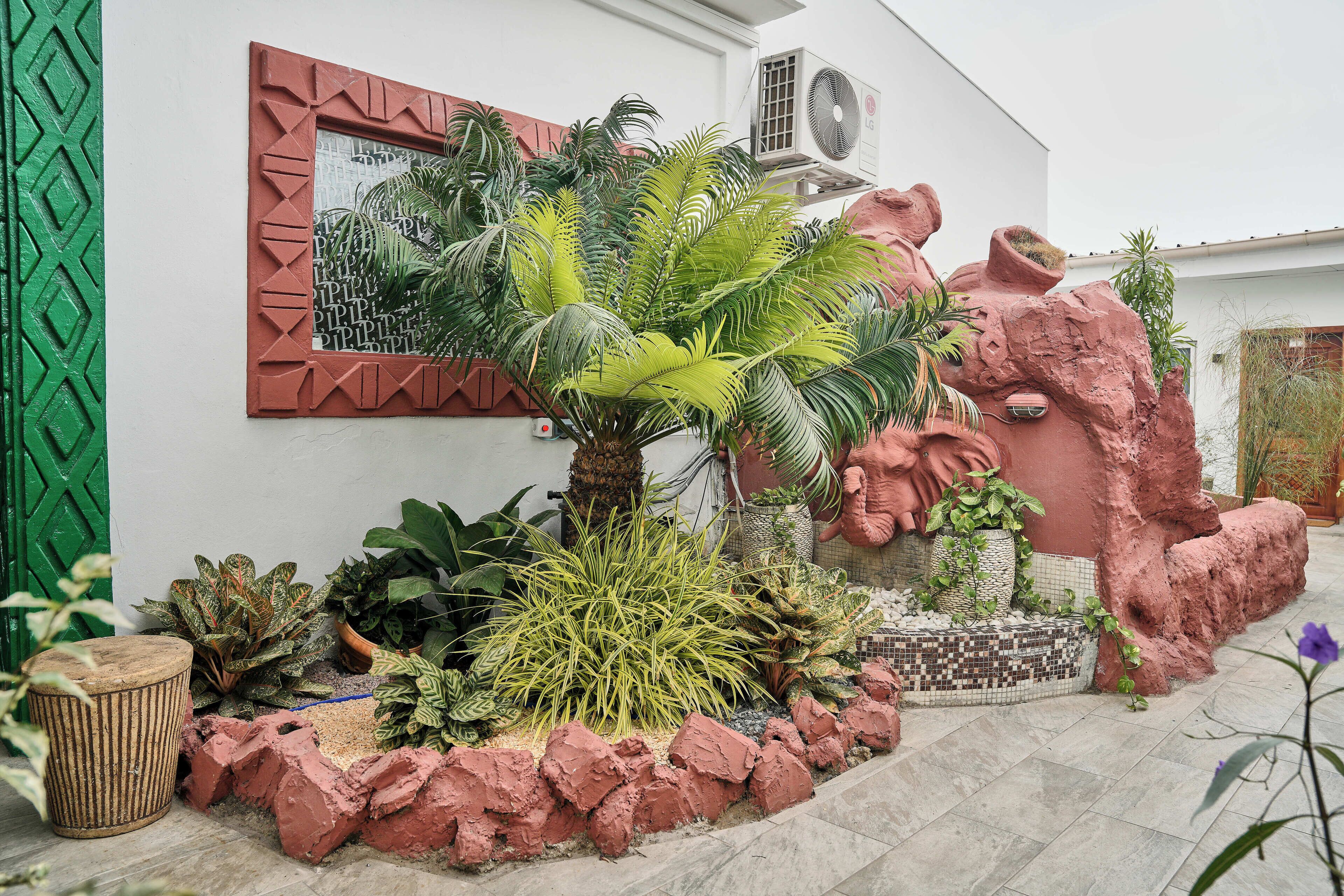 Een tuin met diverse planten, een decoratieve rotsmuur en een betegeld pad.