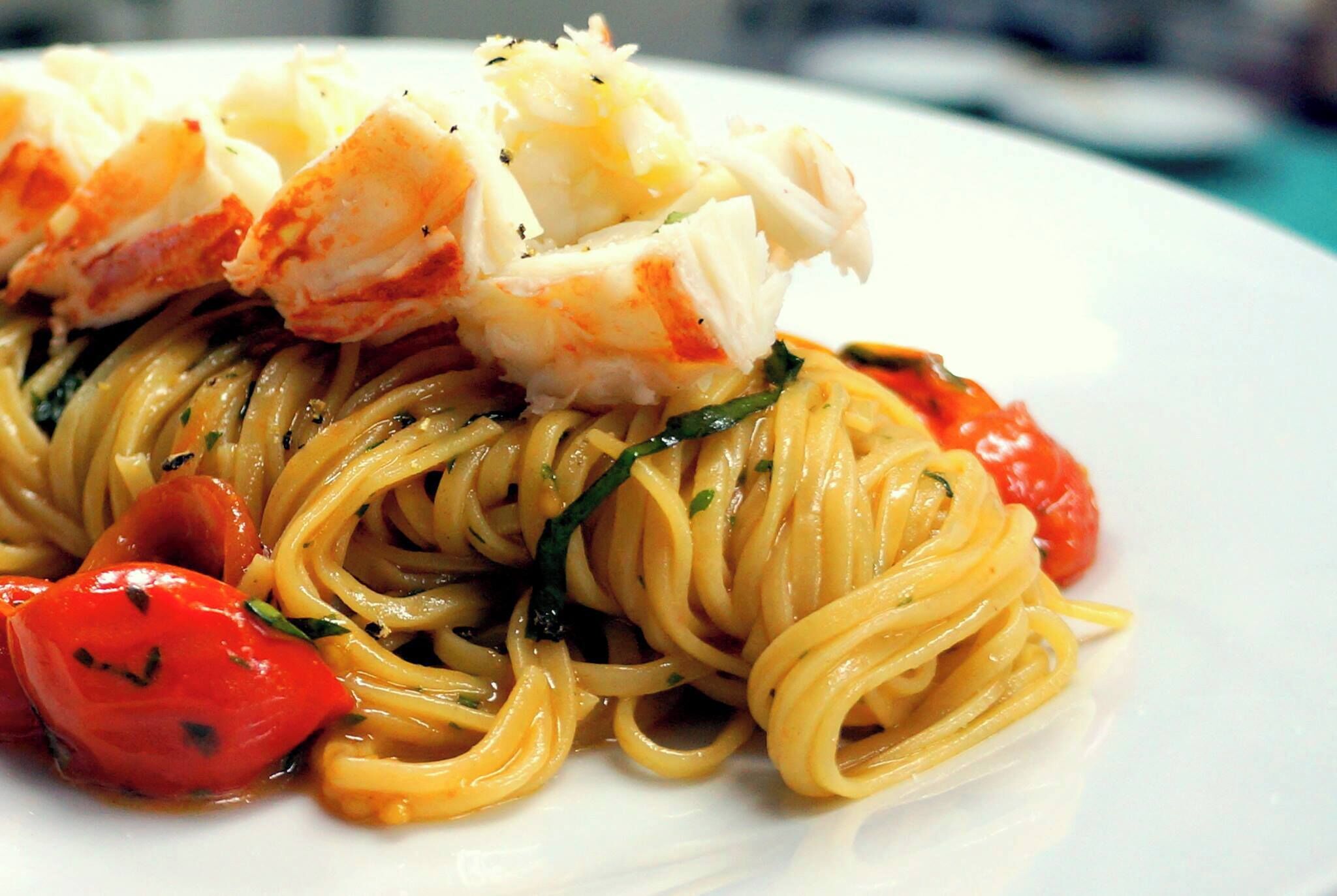 Un plato de espagueti con langosta y tomates cherry.