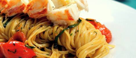 A plate of spaghetti with lobster and cherry tomatoes.