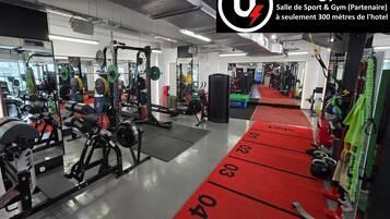 A gym with weightlifting equipment, mirrors, and a red running track.