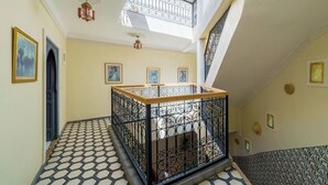 Una escalera con barandilla de hierro forjado, un tragaluz y baldosas de suelo con diseño.