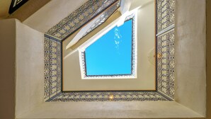 Un tragaluz en una habitación con intrincados diseños de azulejos azules y blancos.