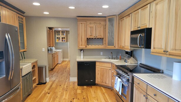 Una cocina moderna con armarios de madera, electrodomésticos de acero inoxidable y piso de madera.