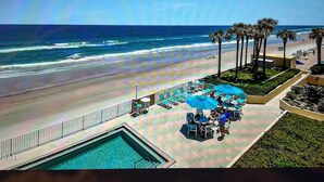Un complexe hôtelier doté d’une piscine, offrant une vue sur la plage et bordé de palmiers.