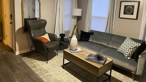 Un salon avec un canapé, un fauteuil, une table basse et un miroir au mur.
