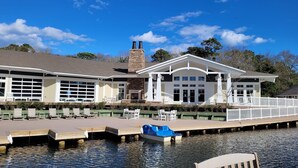 A waterfront building with a dock, outdoor seating, and a stone chimney. - Beachwoods - 2BR/3BA - Great Pools and Amenities! (Kitty Hawk)