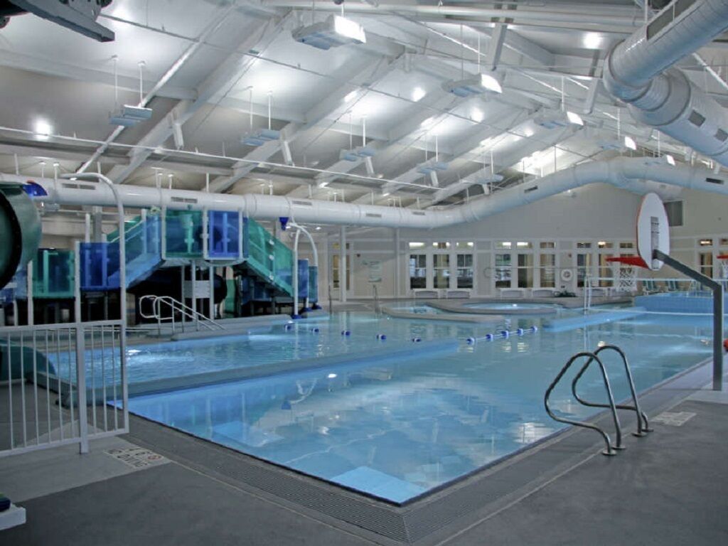 Une piscine intérieure avec des couloirs clairement délimités, un plongeoir et un panier de basket.