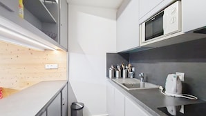 A compact kitchen with a microwave, sink, and utensils on the counter. - Croix de Savoie CX22 CENTER & VIEW 2 Pers. (Châtel)