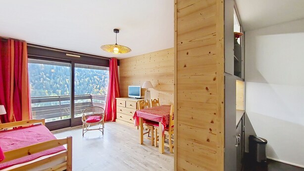 A room with a wooden floor, a bed, a TV, a desk, and a chair. - Croix de Savoie CX22 CENTER & VIEW 2 Pers. (Châtel)