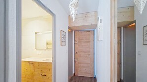 A hallway with wooden flooring, a wooden door, and a mirror on the left wall. - Croix de Savoie CX22 CENTER & VIEW 2 Pers. (Châtel)