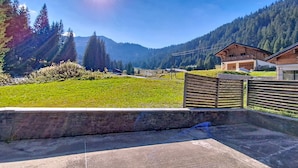 Un paysage rural avec une clôture en bois, un mur de pierre et une montagne en arrière-plan.