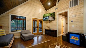 A spacious living room with a large window, a television, and a cozy seating area.