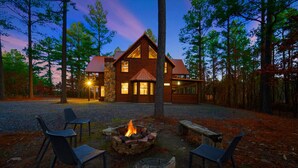 A lodge with a stone facade, wooden exterior, and a fire pit with chairs.