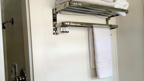 Ein Badezimmer mit Handtuchhalter, gefalteten Handtüchern und einem einzelnen Handtuch an der Wand.