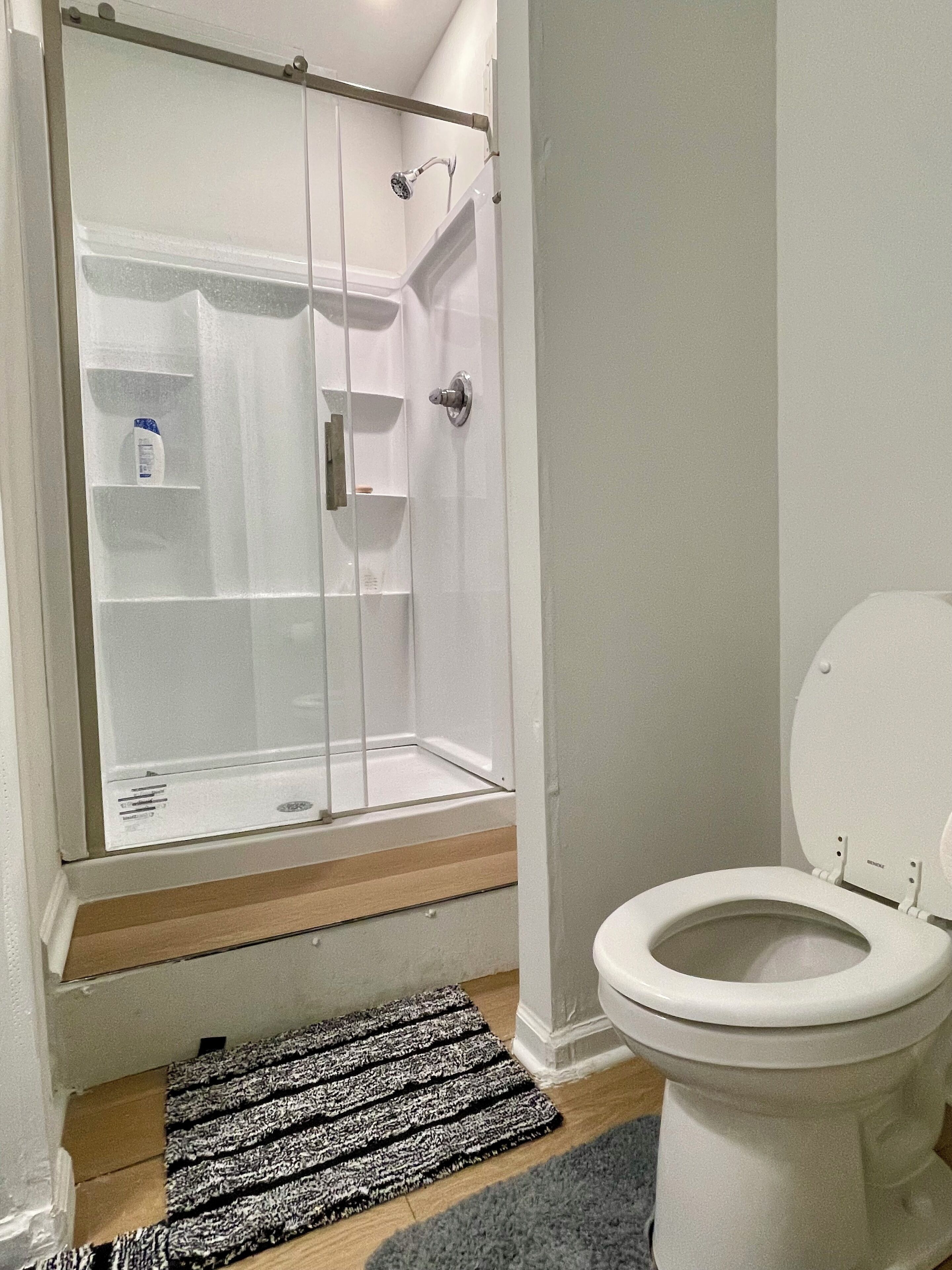 Een badkamer met een douchecabine, toilet en een klein plankje met toiletartikelen.