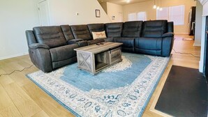 Ein modernes Wohnzimmer mit einer Eckcouch, einem Couchtisch und einem gemusterten Teppich.